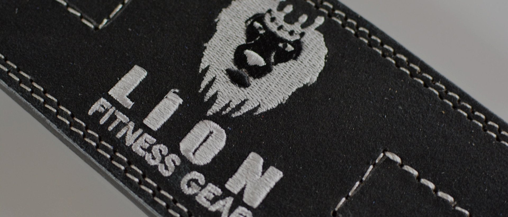 Close-up of the embroidered full-grain leather Lion Fitness Gear weightlifting belt showing double-stitched seams